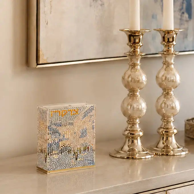 Diamond art craft of Tzedaka box. Design of kosel and words Tzedaka sitting on a buffet near candles.