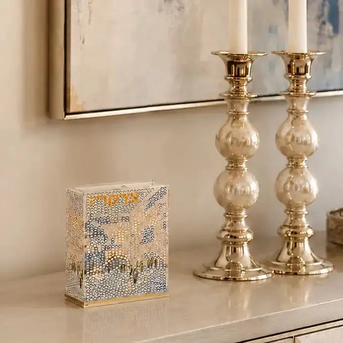 Diamond art craft of Tzedaka box. Design of kosel and words Tzedaka sitting on a buffet near candles.