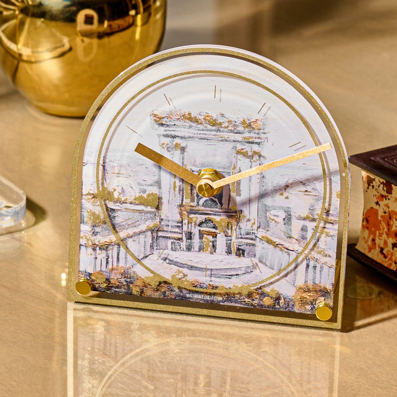 Bais Hamikdash desk clock featuring a watercolor-style Beis Hamikdash illustration with gold accents, arched acrylic frame, and sleek gold clock hands, displayed on a modern tabletop.