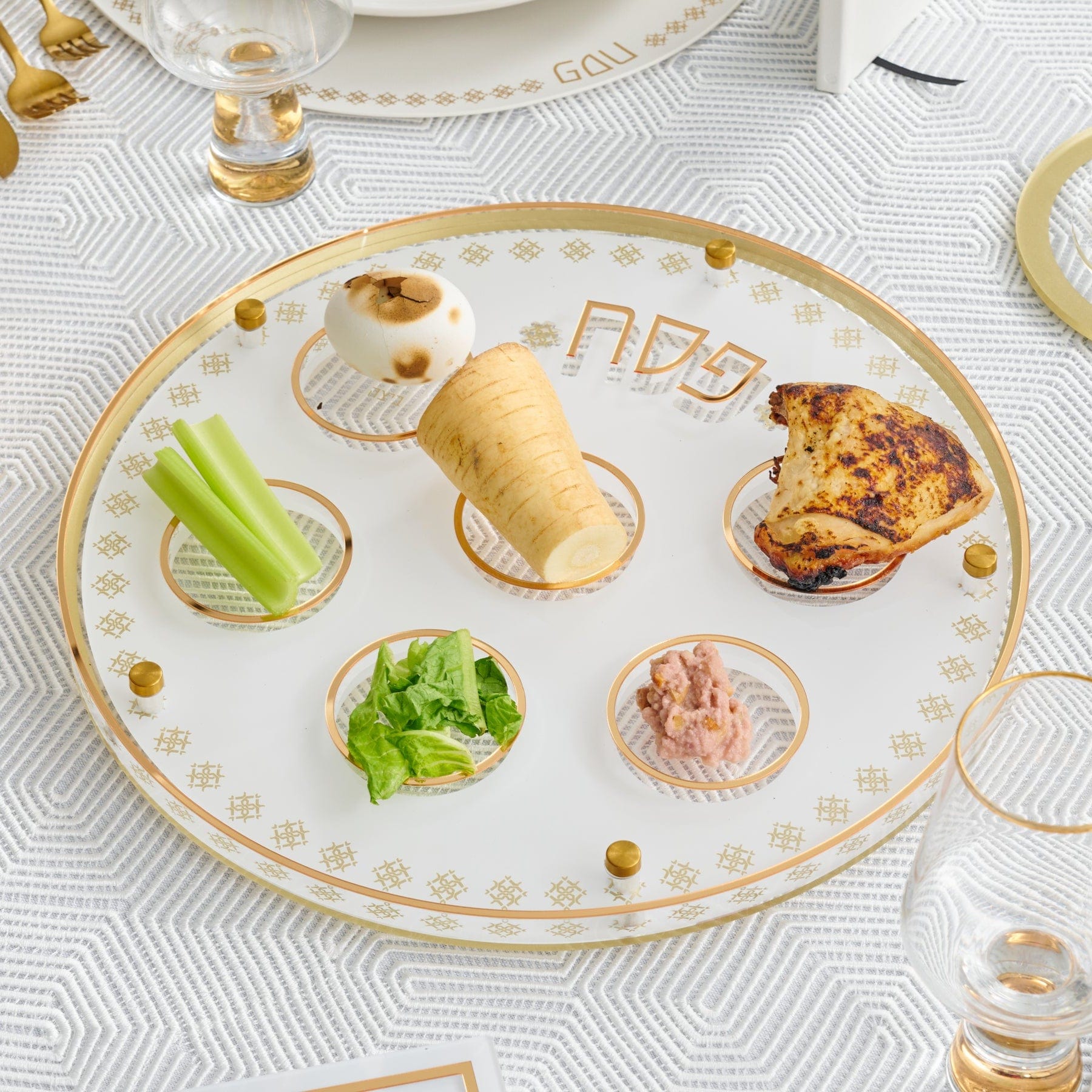 Inspired Seder Plate on a white patterned tablecloth.
