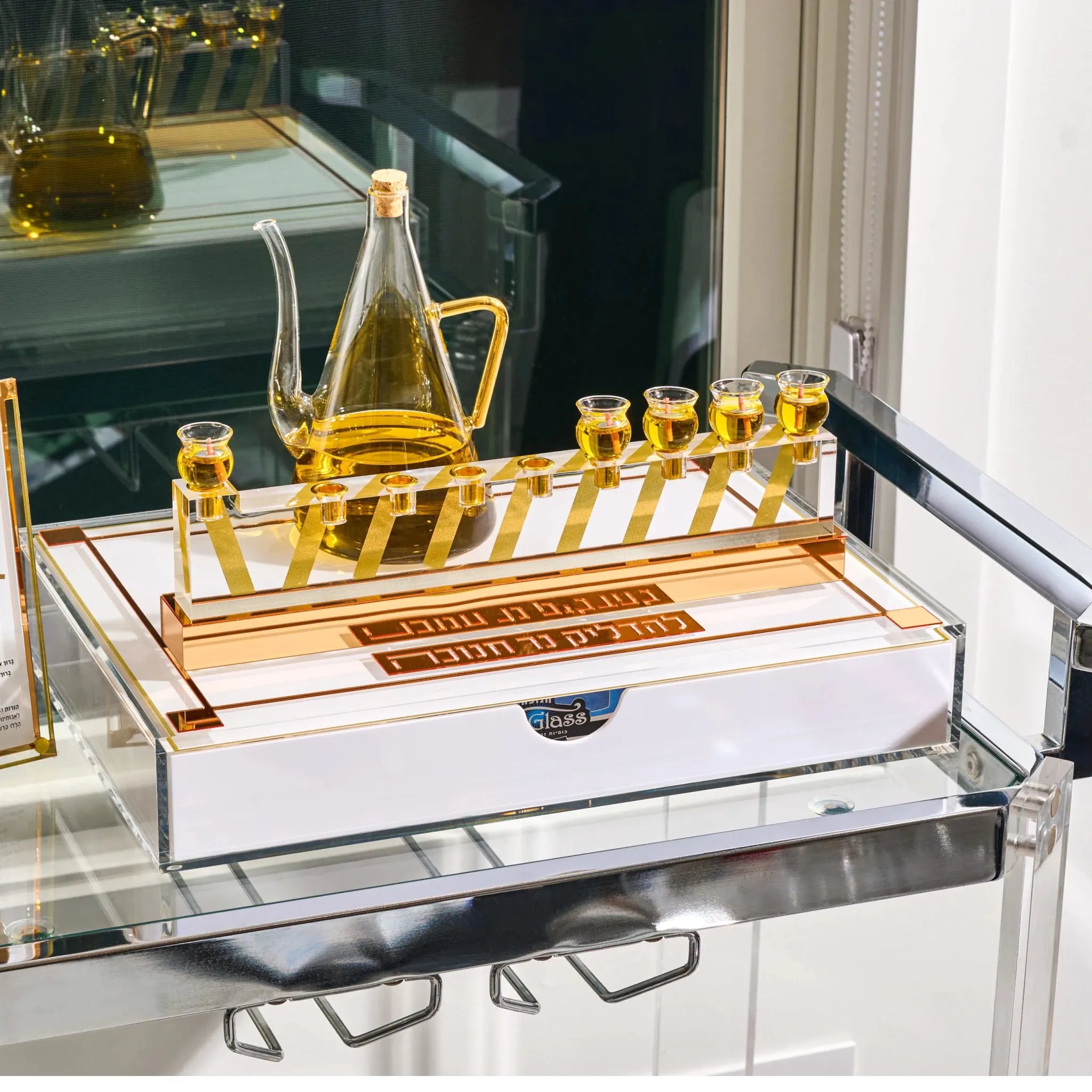 A luxury gold andmenorah tray set on a mirrored glass rolling tray, featuring a glass oil carafe, six small gold cups,