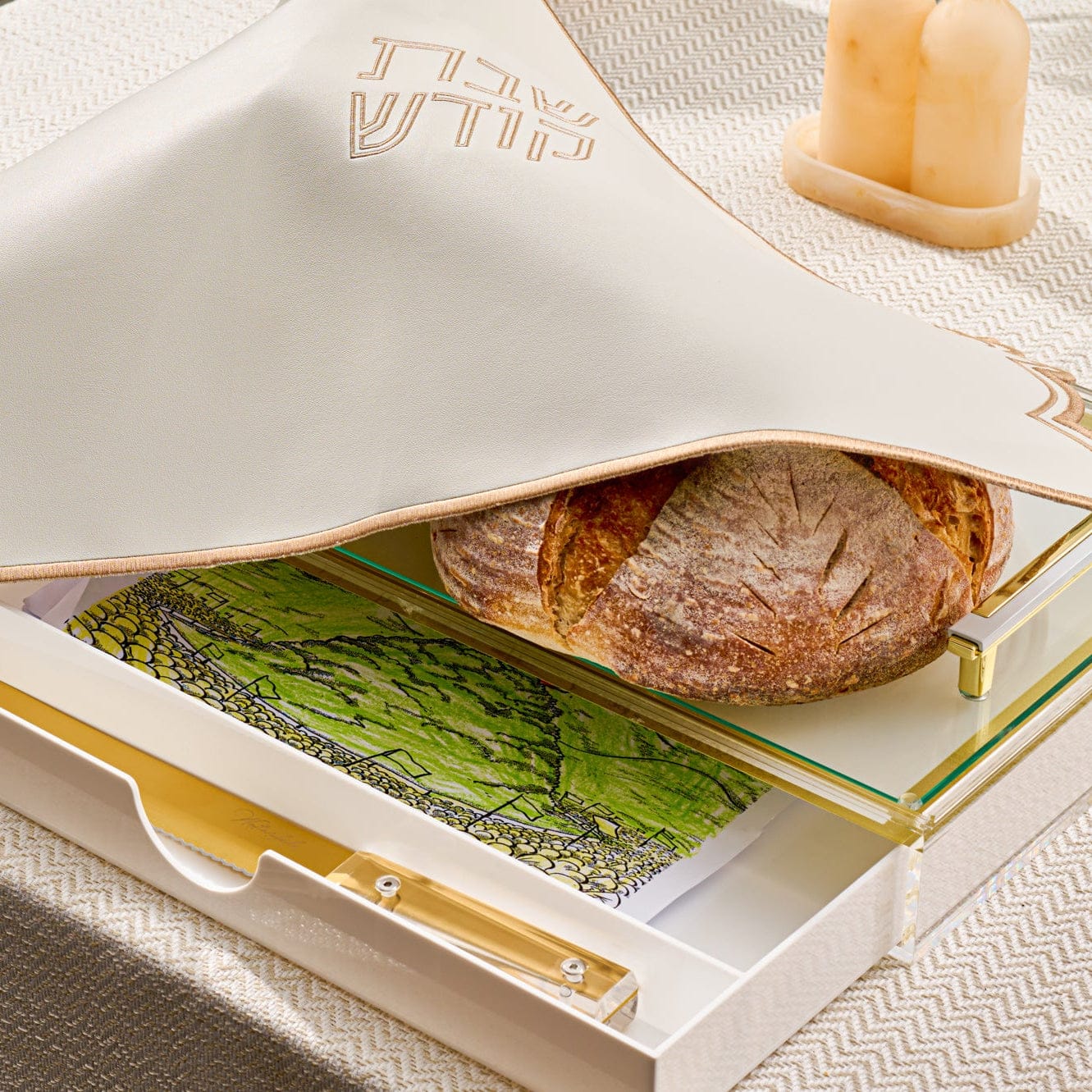 Classic challah board with drawer featuring a frosted “Shabbat Kodesh” challah cover, glass cutting surface with gold accents, and a hidden drawer for accessories, displayed with artisan challah bread.