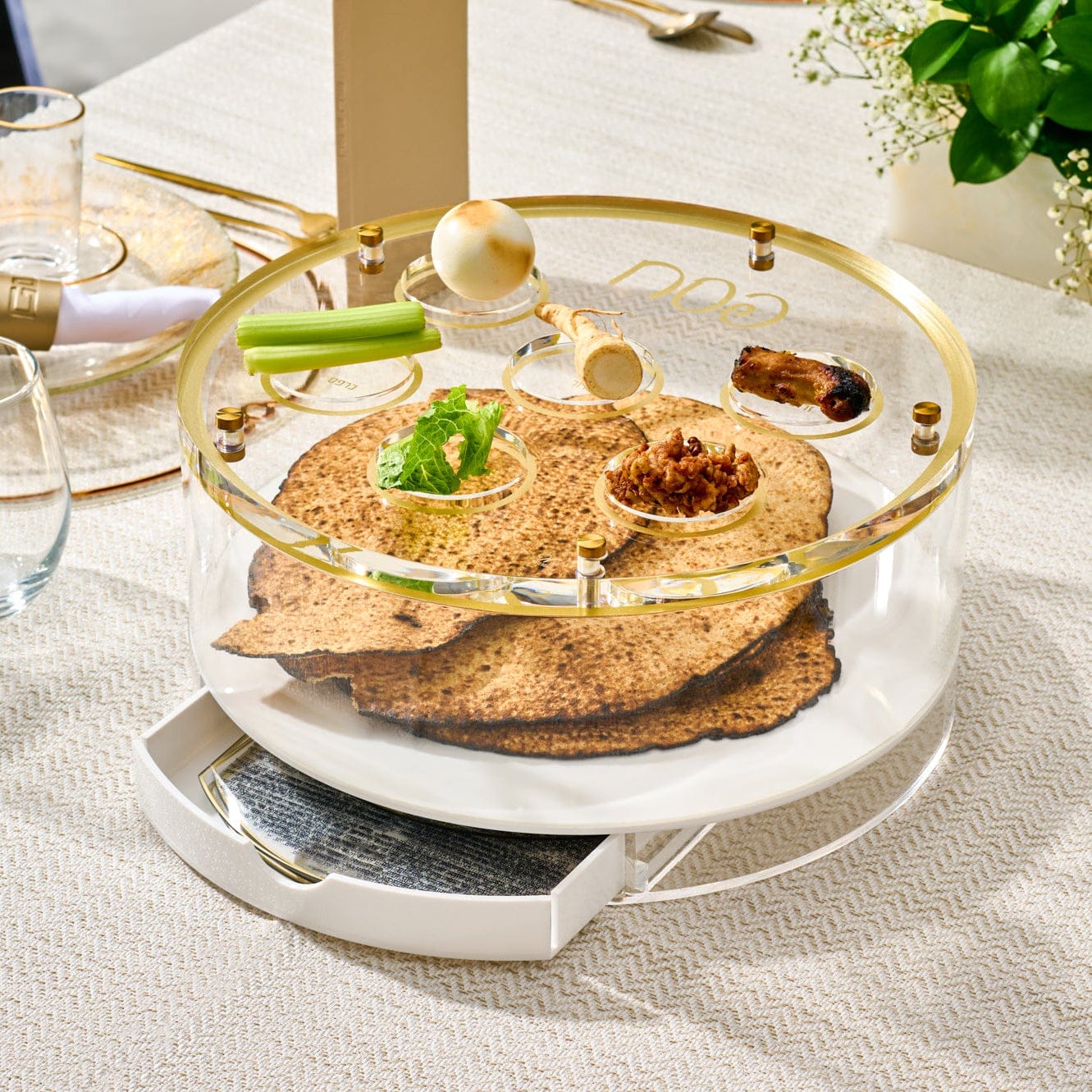 Classic Script bencher set matzah box featuring a clear acrylic and gold Seder plate design with labeled compartments, displaying matzah and traditional Pesach symbols on an elegant table setting.