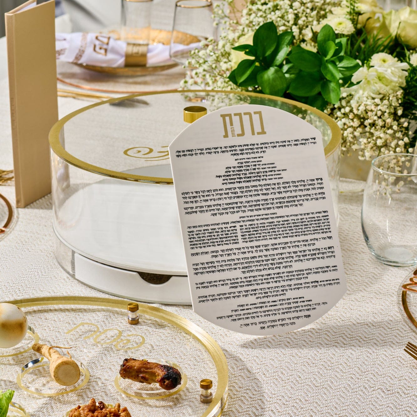 Classic Script bencher set matzah box featuring a clear acrylic and gold Seder plate design with labeled compartments, displaying matzah and traditional Pesach symbols on an elegant table setting.