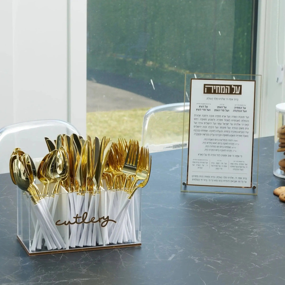 Classic Waterdale silverware caddy with gold-toned metal utensil holder displayed on counter with event card nearby.