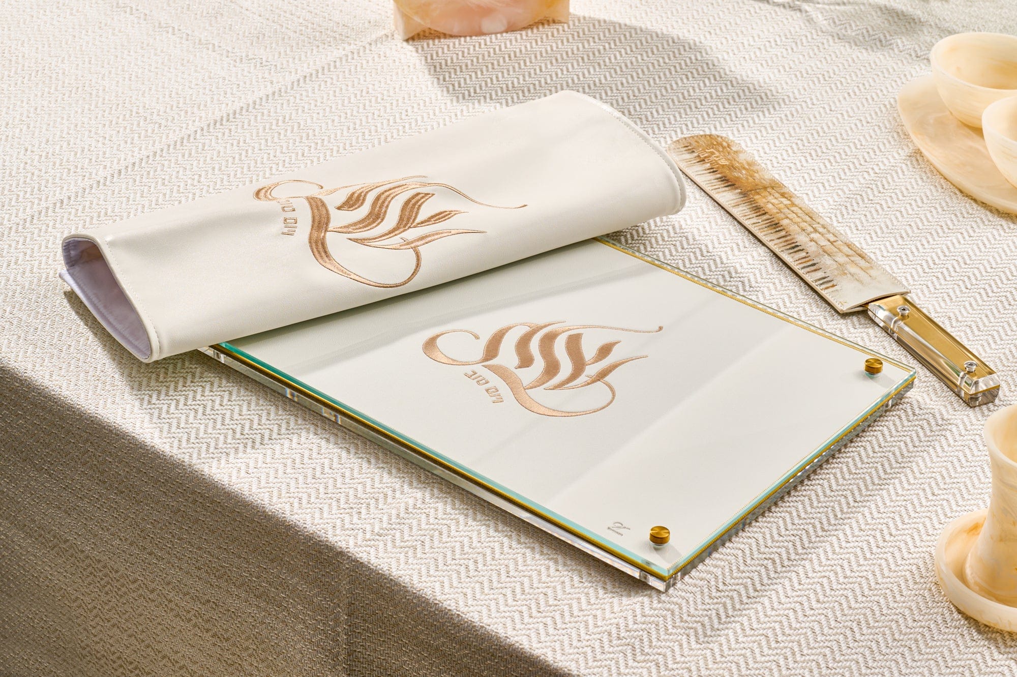 Embroidered regal challah board with an intricate gold and white floral pattern and crystal handles on a white marble surface.