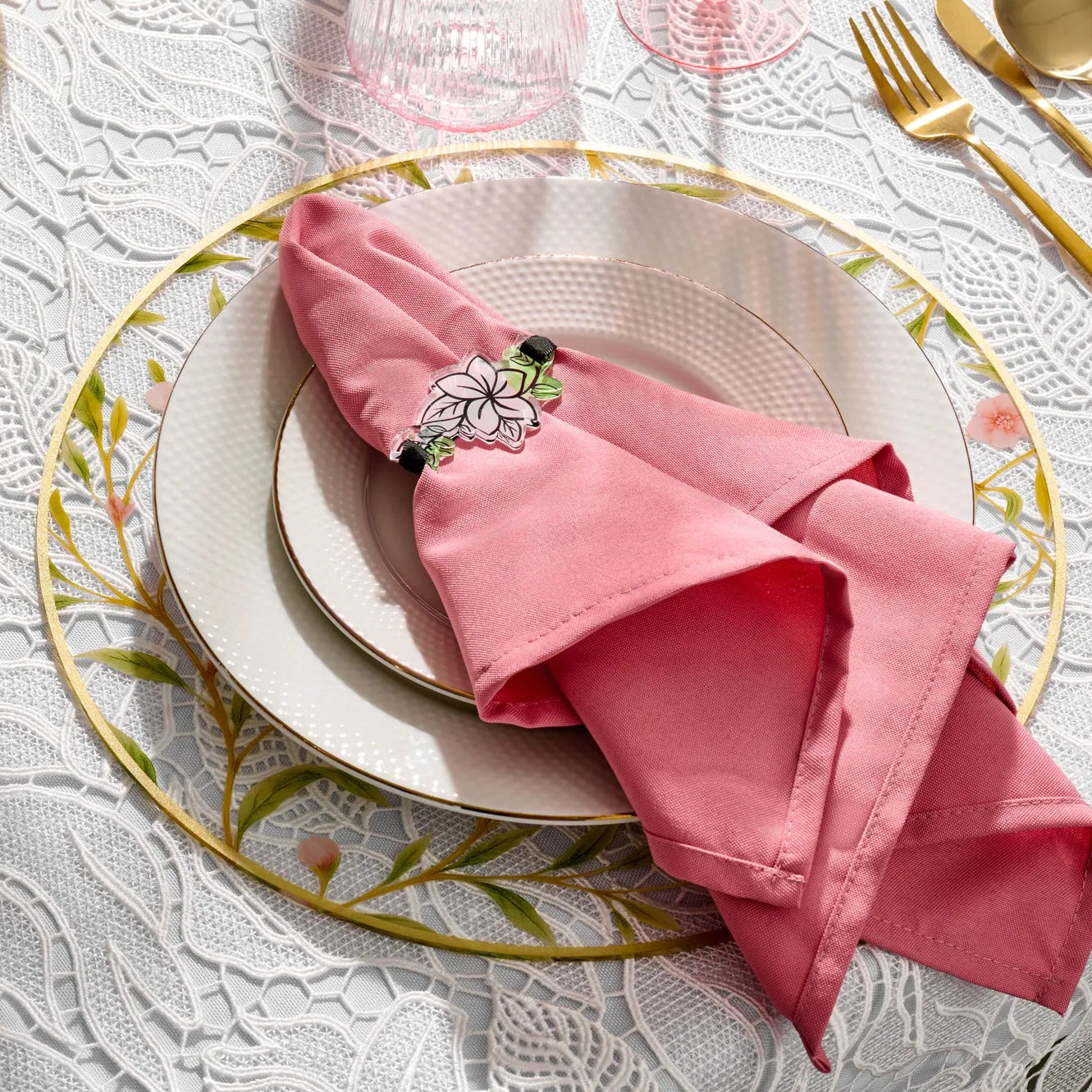Pink and green lucite floral napkin wrap around a pink napkin set on a plate and floral bird charger.