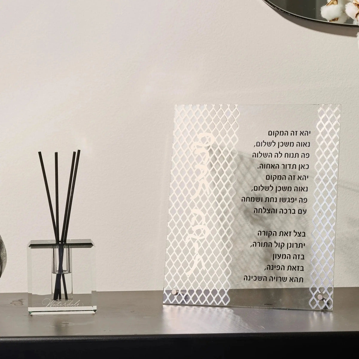 White laser cut tabletop Birchas Habayis plaque displayed next to a reed diffuser on a dark shelf