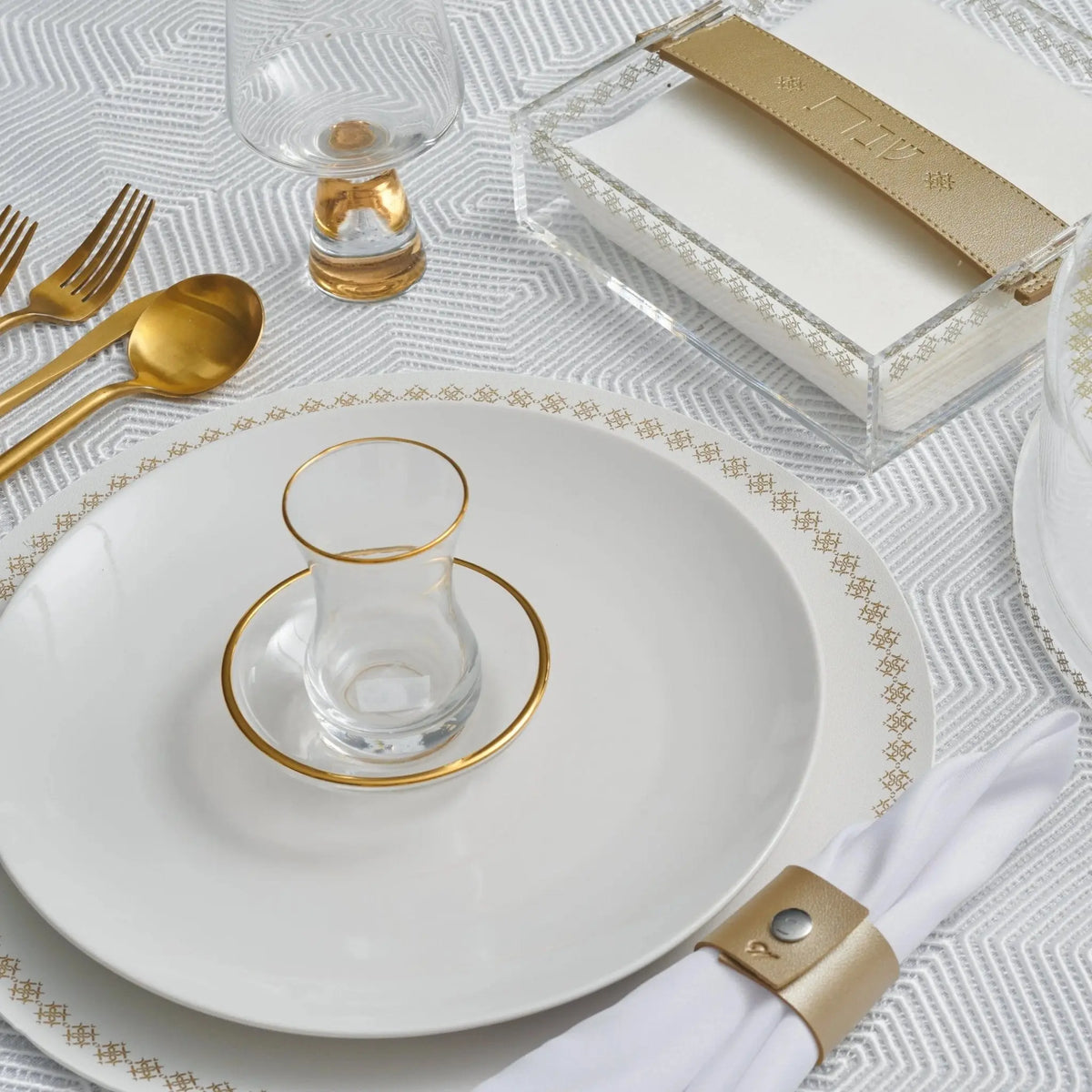 Gold-rimmed round leather charger plate displayed on white table setting with gold utensils and glassware for elegant dining.