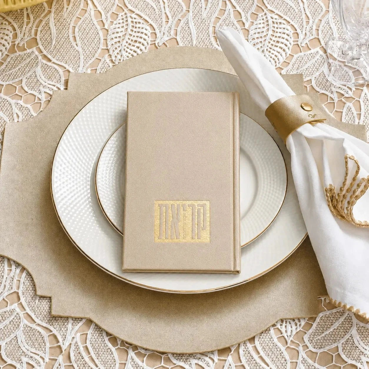 Cream leather Shema prayer book on white plate with napkin and utensils in elegant table setting