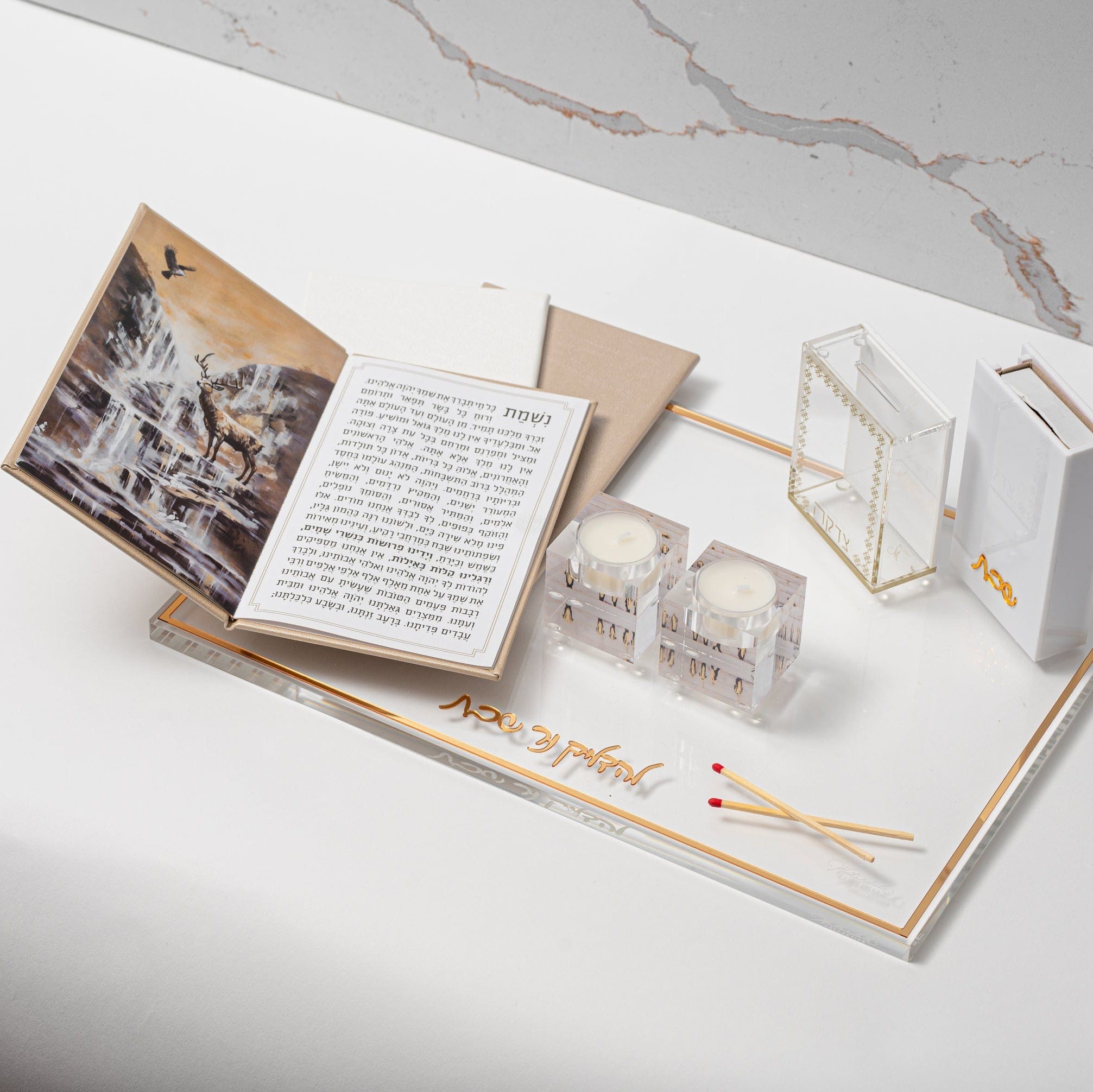 Gold Leather Painted Nishmas Booklet opened on top of a tray with tealight holder and matches| Waterdale Collection