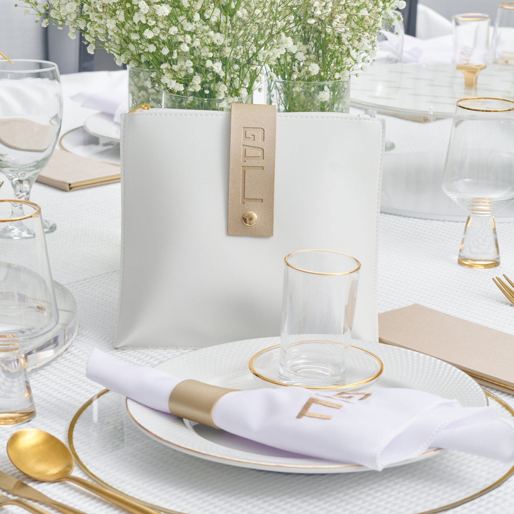 Leather Square Gebrokst Bag with gold accent tag displayed on an elegant white and gold Passover table setting