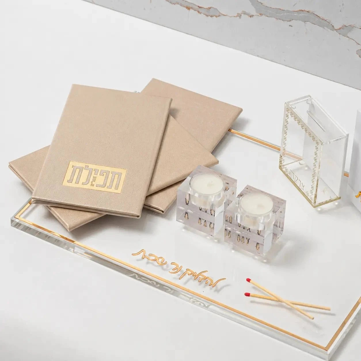 Tan leather Tefillas Hashlah prayer book displayed with matching accessories and prayer cards on white surface