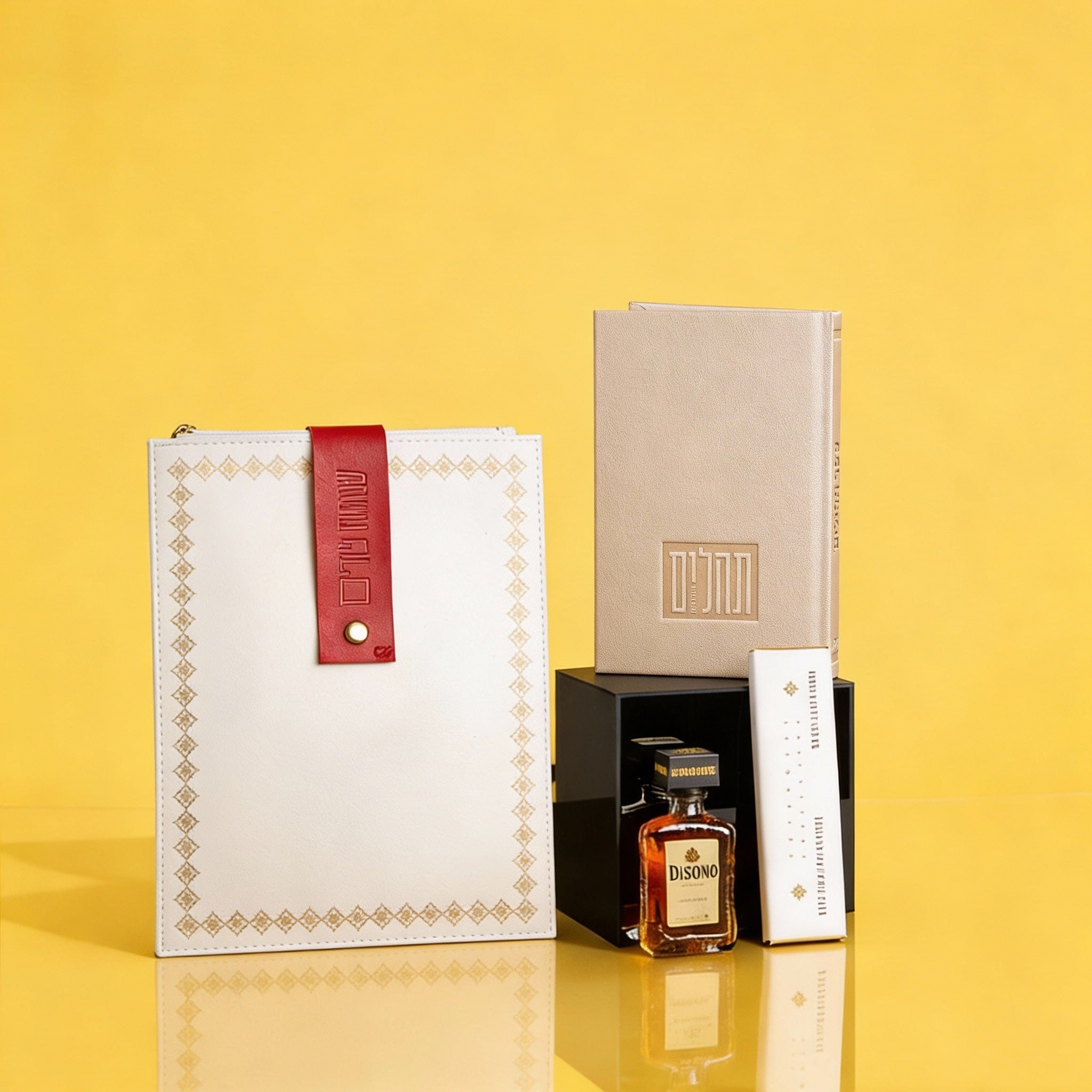 Luxury Mishloach Manot gift set featuring a gold-embossed Tehillim book, a white leatherette pouch with a red "Simchat Purim" strap, and a mini Disaronno liqueur.