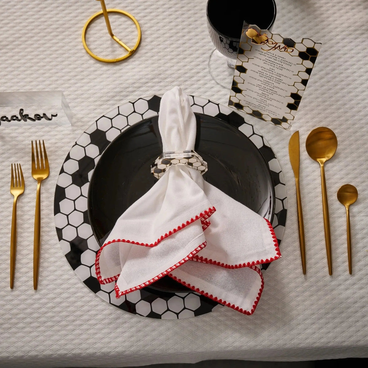 Black onyx napkin rings with pearl beaded trim displayed on a formal place setting with gold flatware and white linens.