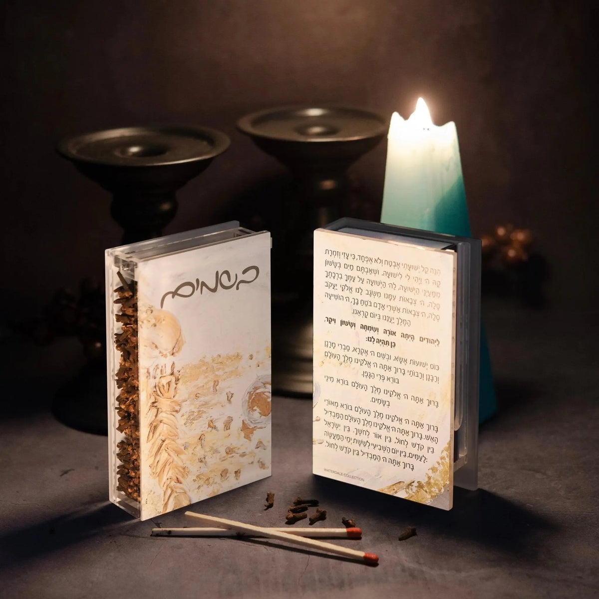 Painted Gold Havdalah matchbox holder with cream and gold design, displayed open next to matches and lit Havdalah candle with black ceremonial cups.