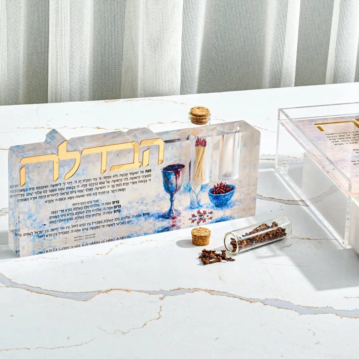 Painted Havdalah sculpture set with blue ceramic tray, candlestick, and ritual objects arranged on white marble surface.