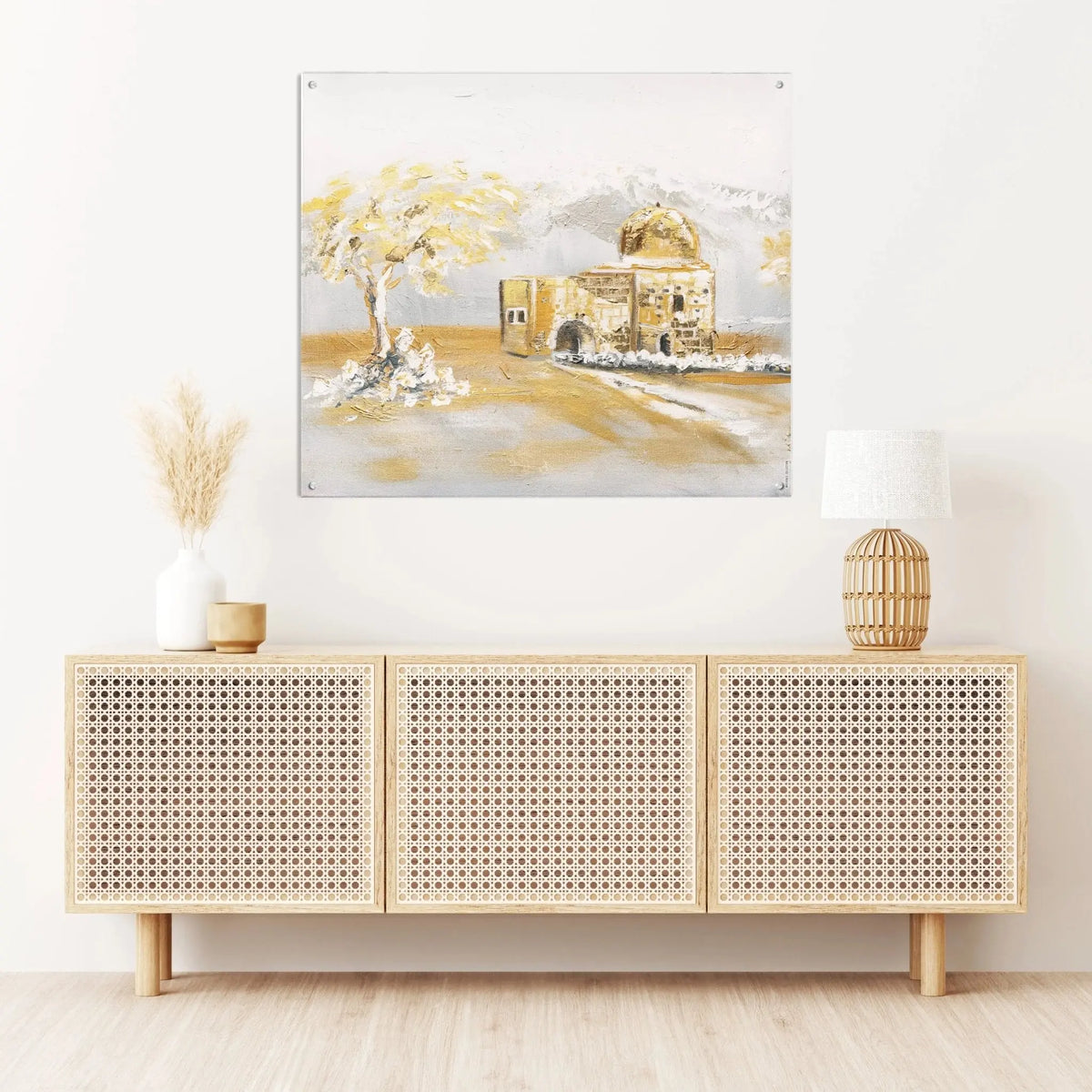 Painted Kever Rochel framed wall art displayed above a light wood sideboard with rattan doors in a bright room.