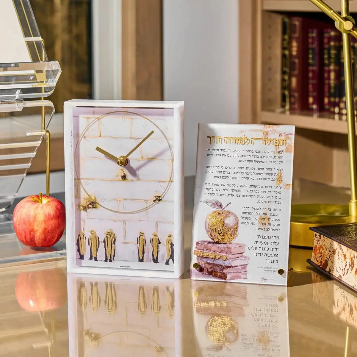 Painted Tefila L'Moreh Derech lucite card displaying Hebrew text and watercolor illustrations in warm tones, displayed on desk with apple and flowers