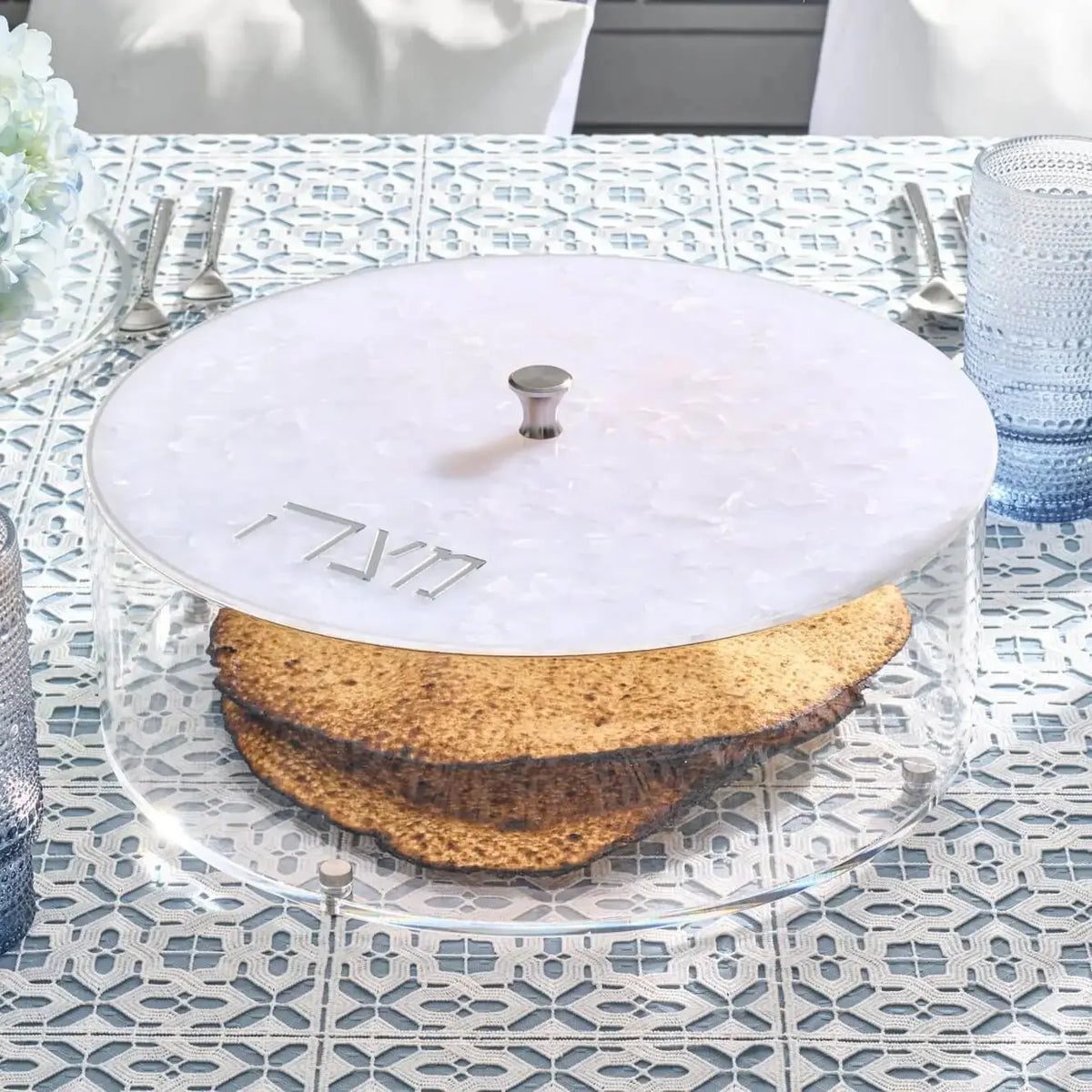 Pearlstone matzah box with white marble lid and cork base, displayed on a patterned surface with Passover tabletop decor.