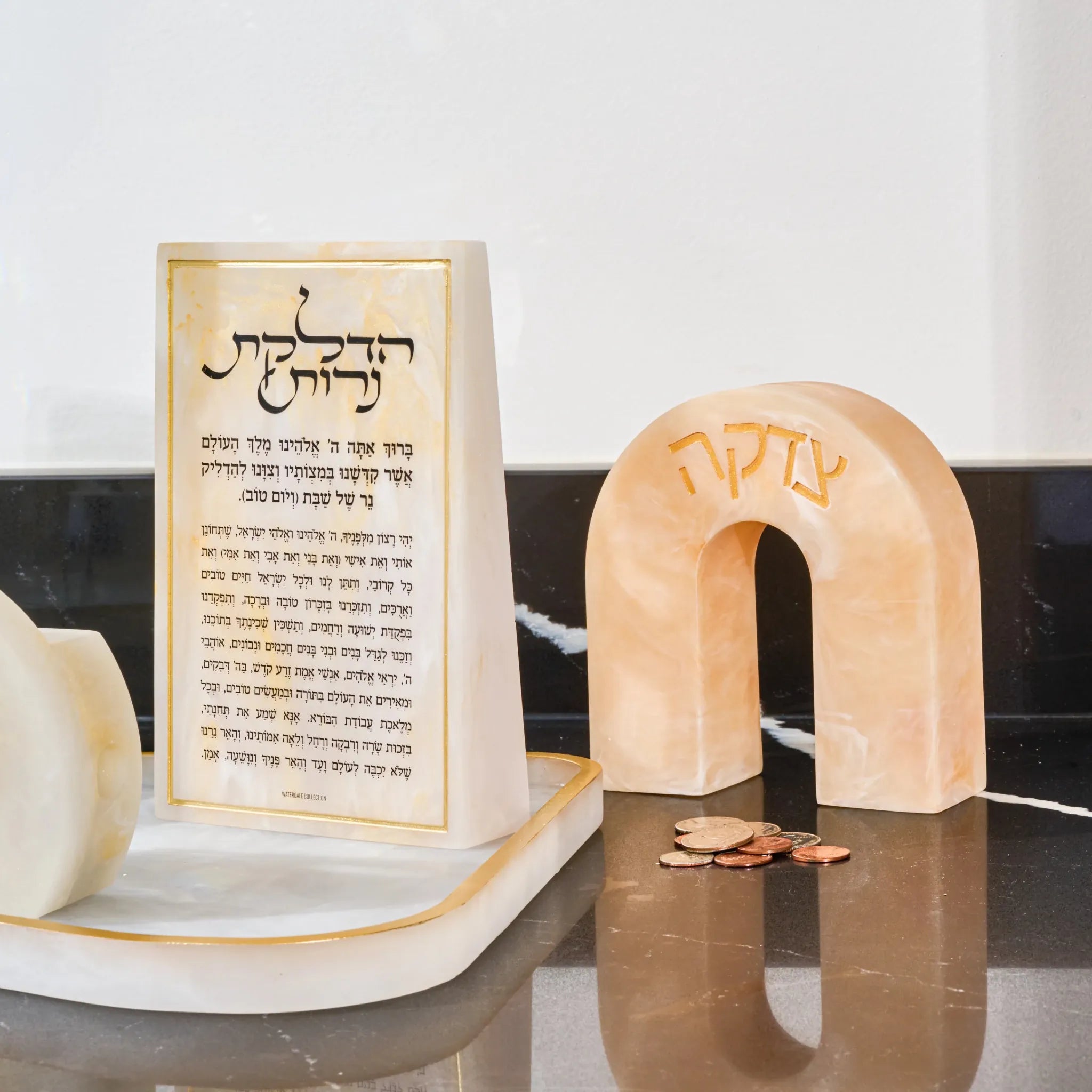 Cream resin arch tzedakah box with Hebrew text, displayed near a resin base with resin brachos block