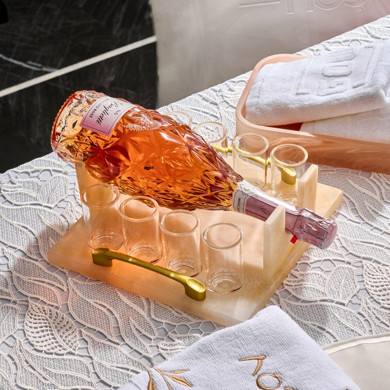 Resin liquor and wine serving set featuring a marble-look tray with gold handle, crystal bottle of rosé, and matching shot glasses, styled on an elegant lace tablecloth. | Waterdale Collection