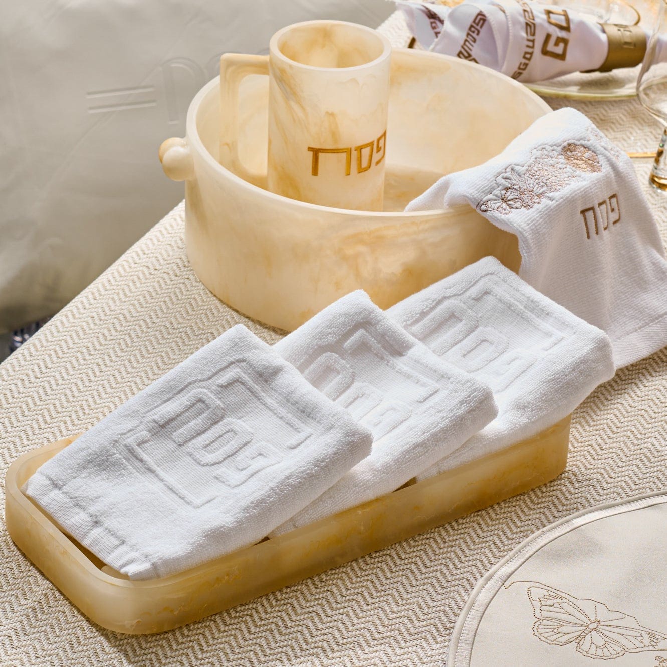Resin Pesach towel box in marbled cream finish holding white guest towels with embossed design, displayed alongside matching Pesach accessories.
