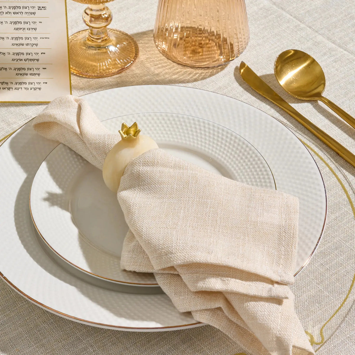 Gold resin pomegranate napkin ring on a folded napkin for Yom Tov