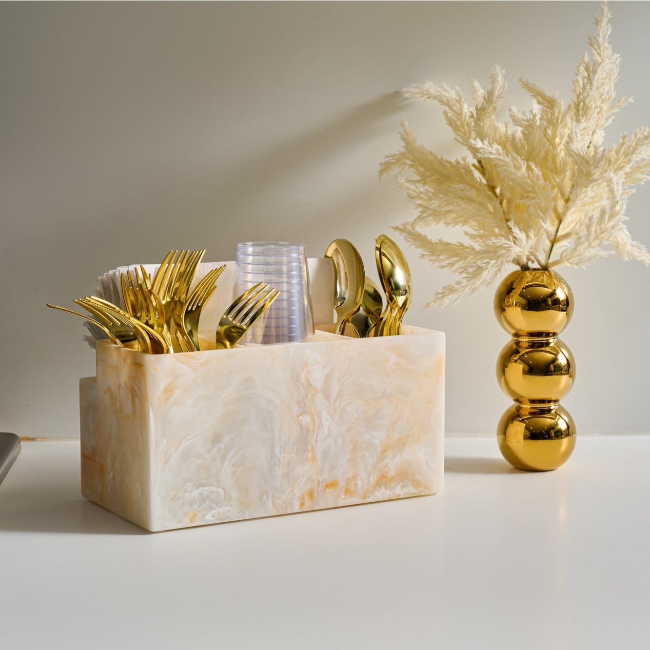 Resin silverware caddy with a marble-look finish, organized tabletop holder for cutlery and napkins.