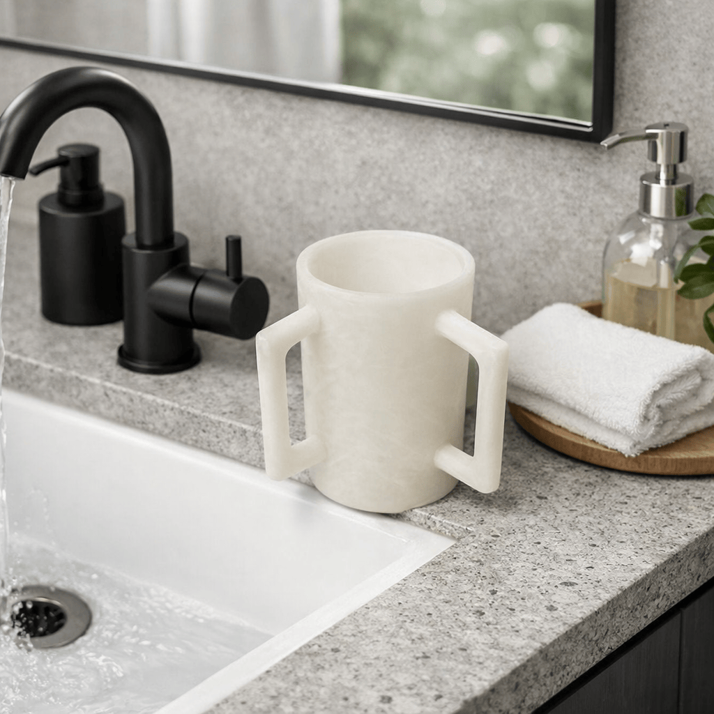 White resin washing cup on a marble sink with water running - Waterdale Collection