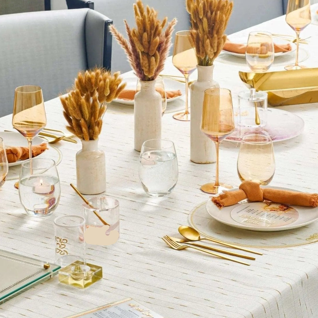 Rosh Hashanah 2024 rustic tablescape with white linens, gold wheat stems, place settings, and neutral décor on dining table