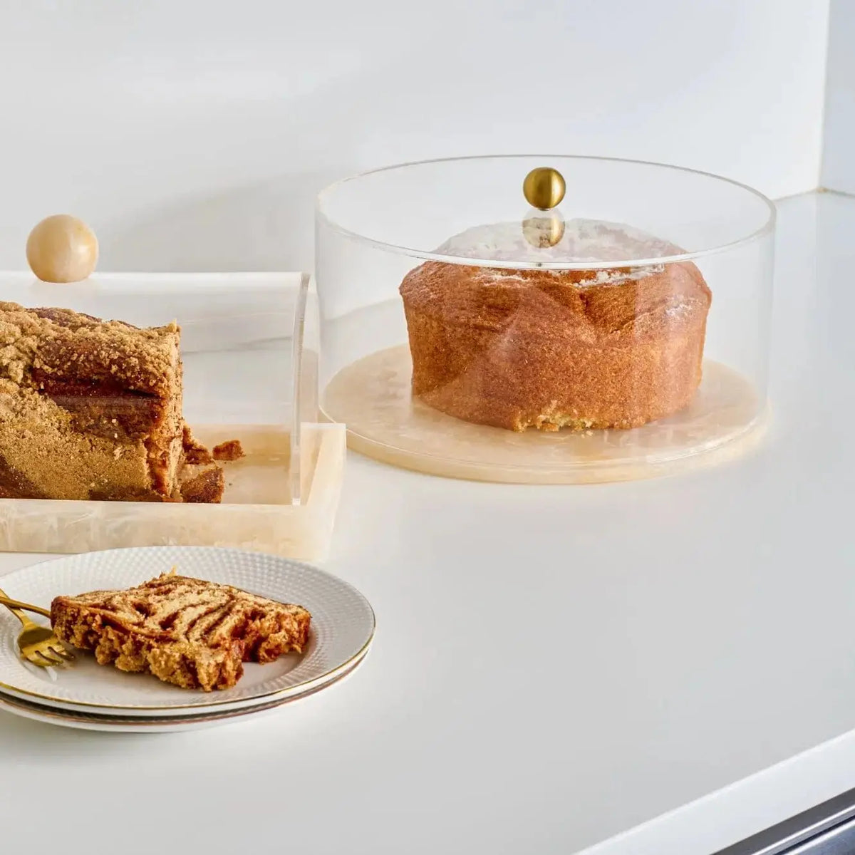 Round clear resin cake dome with gold accent displaying fresh baked cake, serveware for entertaining and holiday tables.