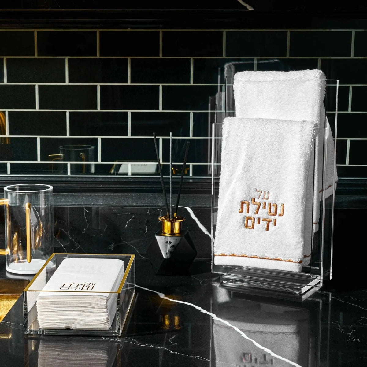 Waterdale Collection scalloped hand towel in black and gold displayed on bathroom vanity counter next to soap dispenser