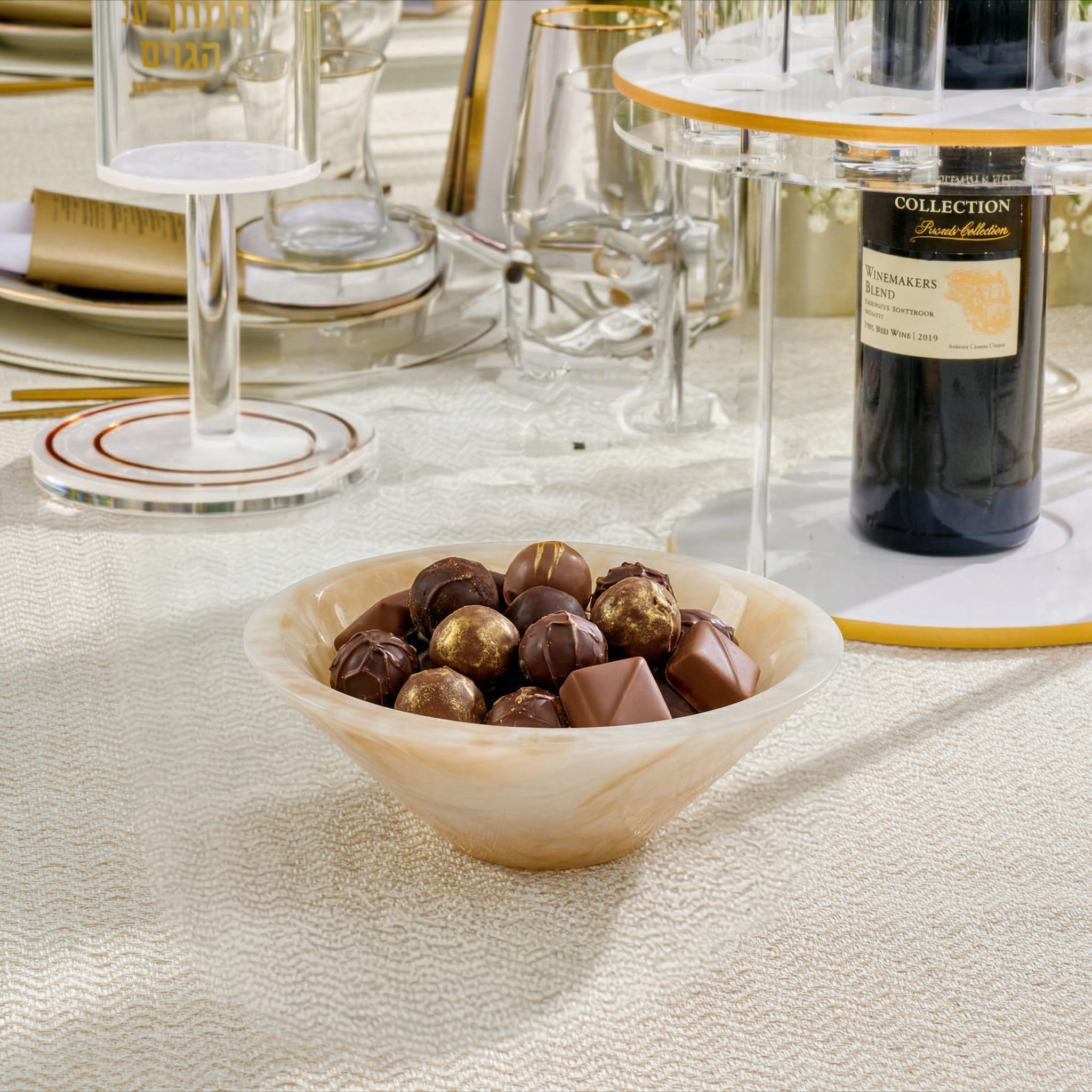 Small cream marble resin round bowl filled with chocolates on a set table for elegant holiday hosting and modern home decor.