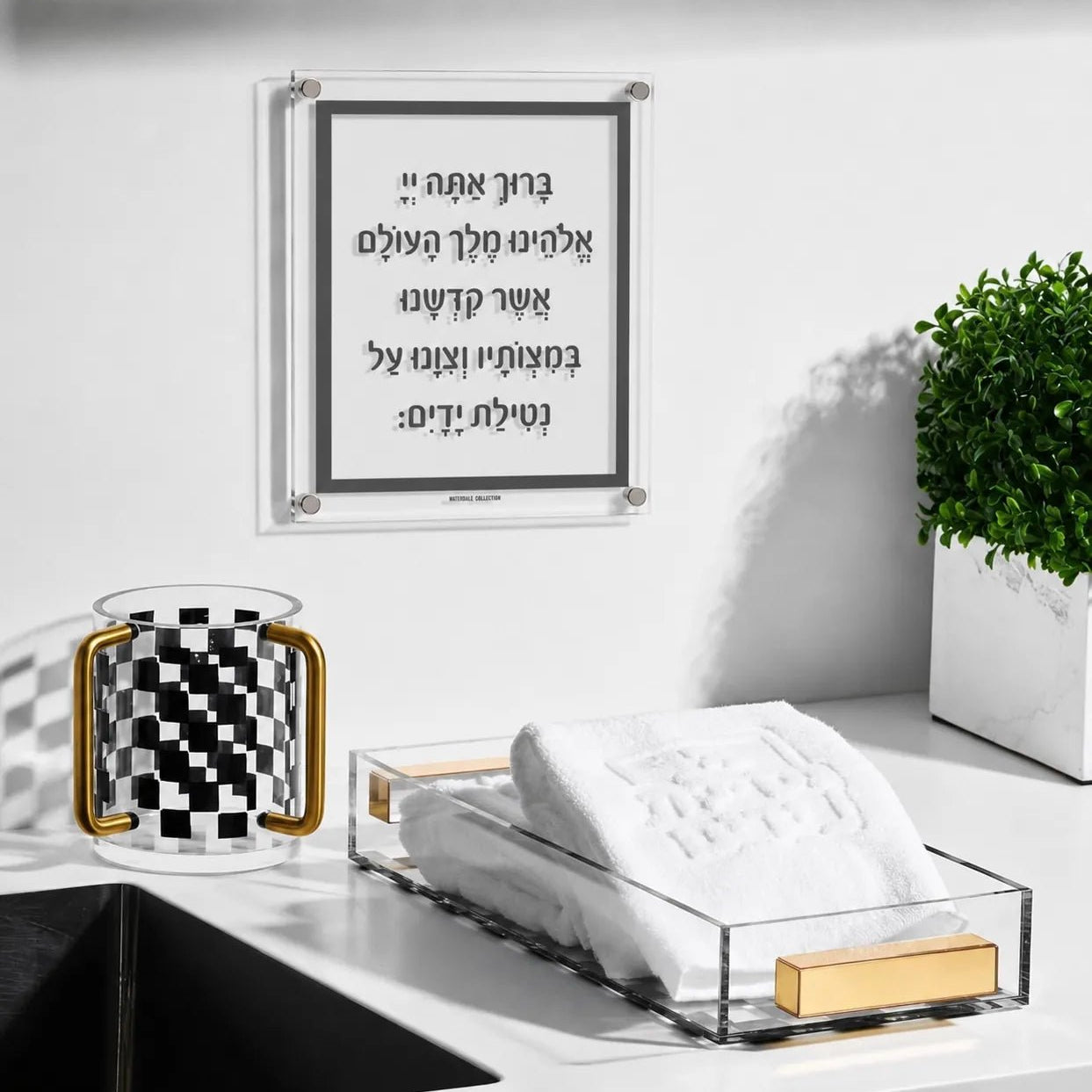 Traditional Al Netilas Yadayim acrylic plaque displayed above a bathroom sink alongside an Onyx checkered washing cup and acrylic guest towel holder — Waterdale Collection