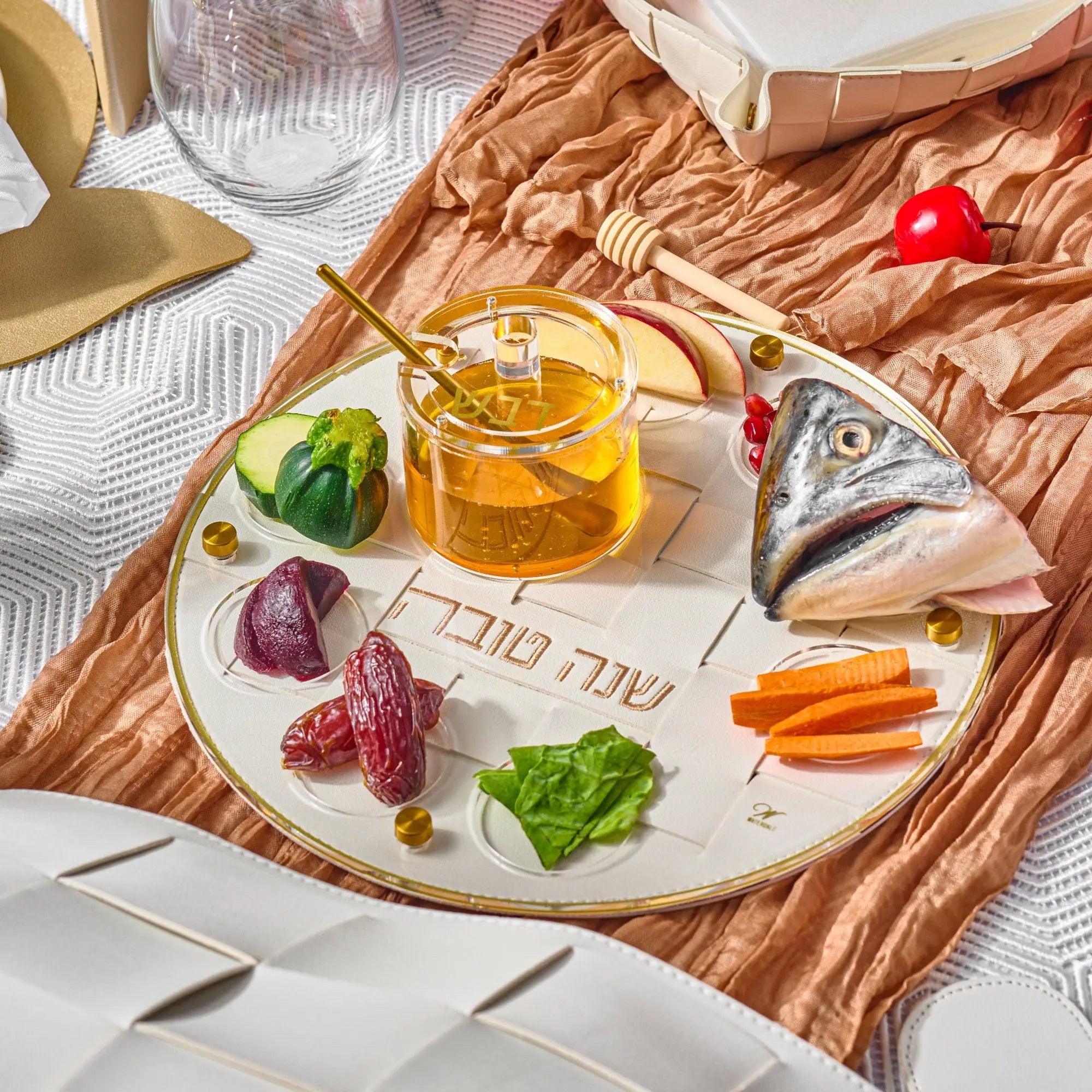 Gold Woven Simanim Tray with fish head, honey dish, and other items on top of it