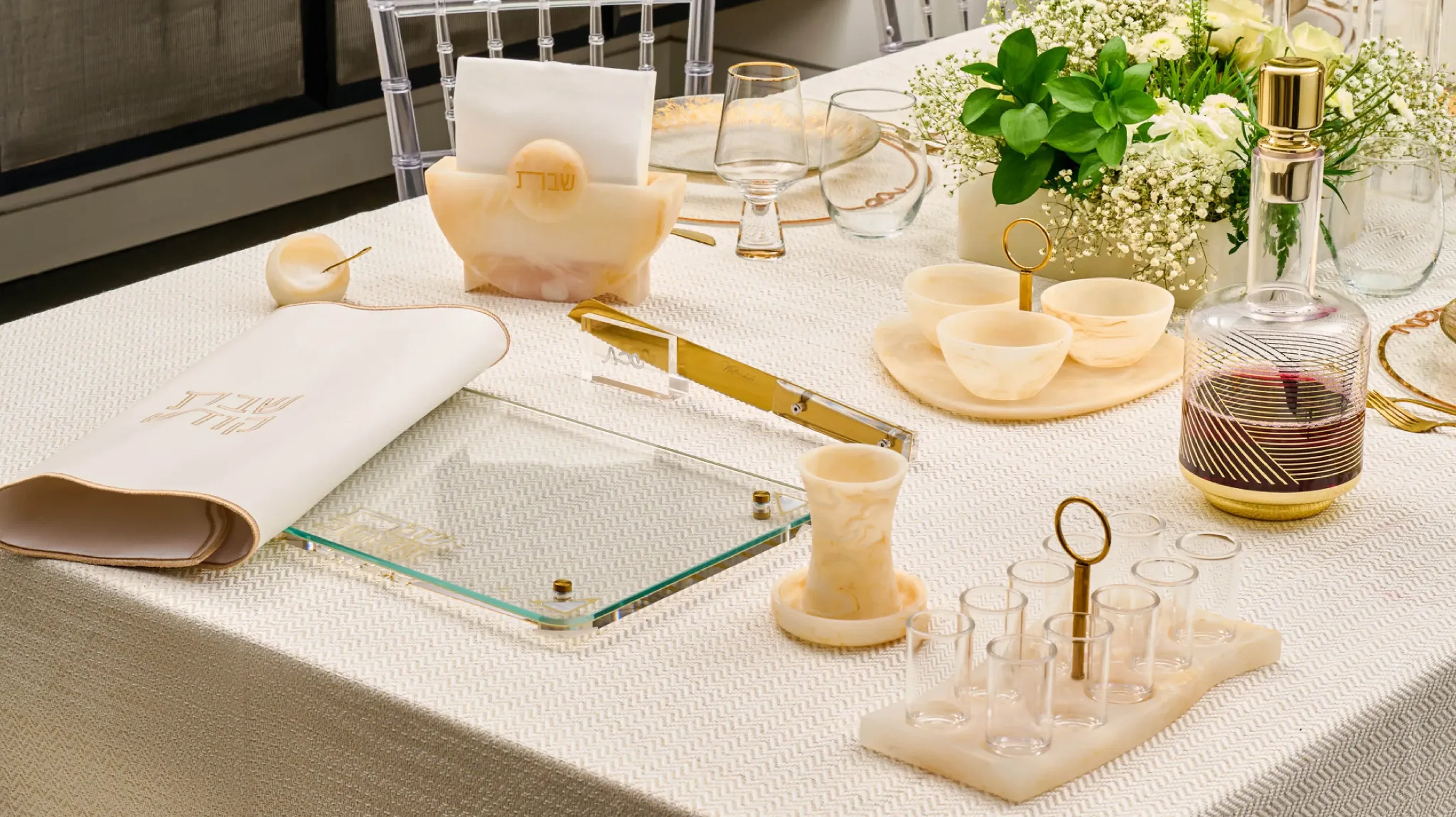 Modern resin Judaica collection with challah board, kiddush cup, serving bowls, and wine decanter on a Shabbat table