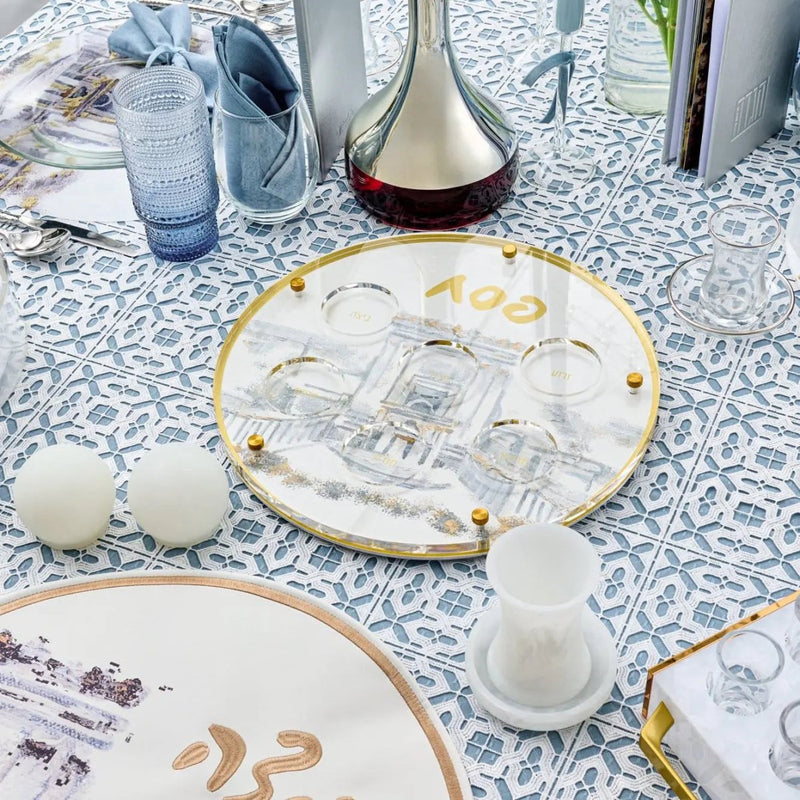 Painted Bais Hamikdash Seder Plate with gold trim displayed on patterned tablecloth, showing detailed ceramic design for Pesach holiday meals.