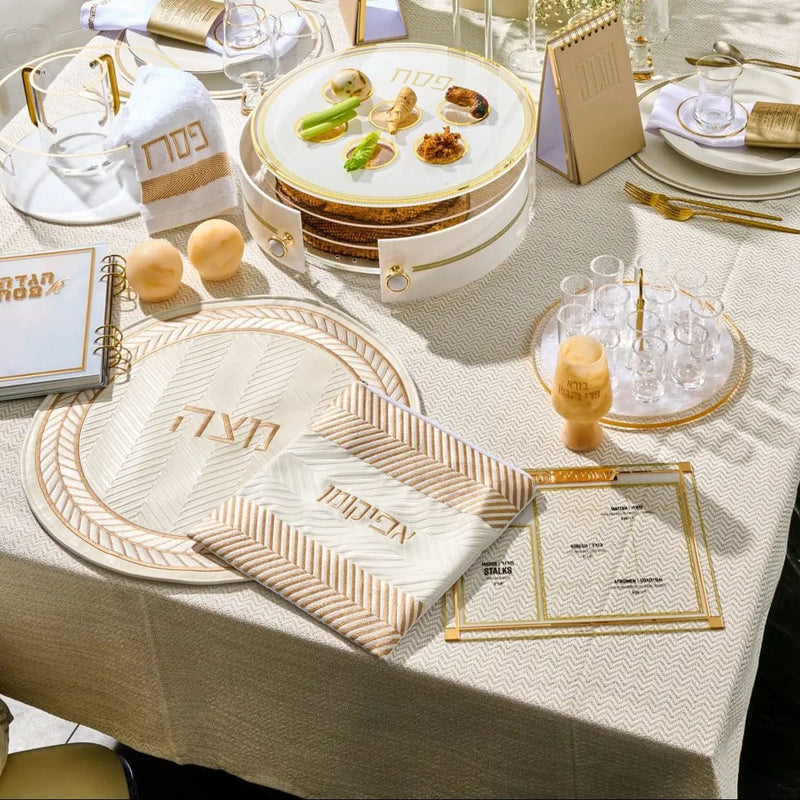 Beige herringbone matzah cover with embroidered details displayed on a holiday table setting with place cards and tableware.