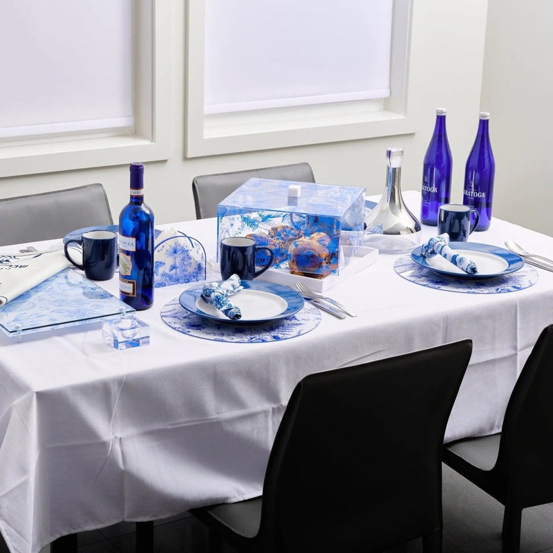 Shavuos French Toile 2024 tablescape with blue and white patterned dinnerware, linens, and floral centerpiece on round table.