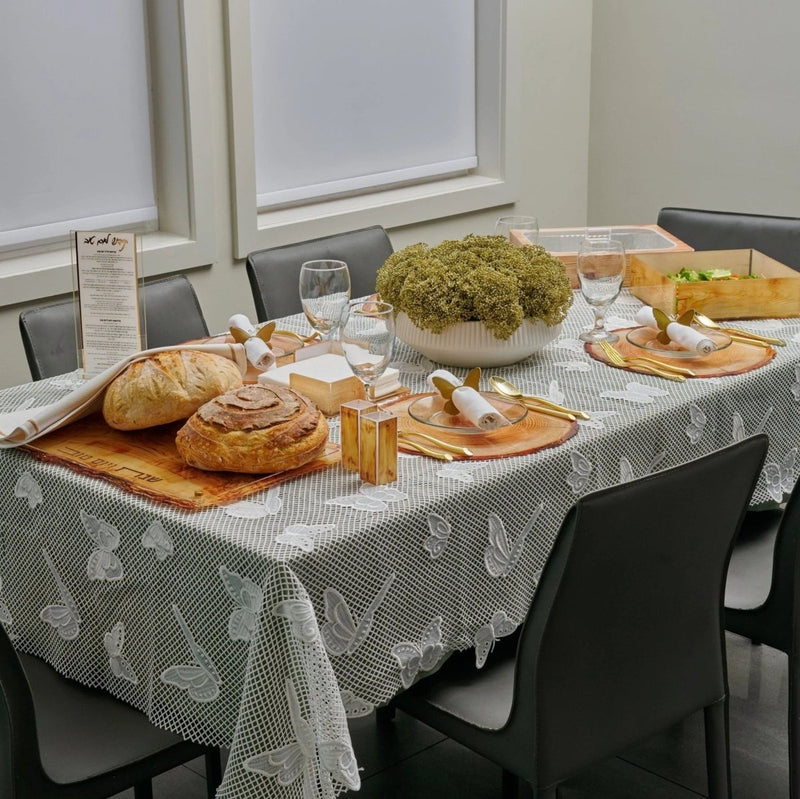 Onyx Butterfly Tablecloth with gray and white pattern displayed on table set with bread, salads, and dishes for Shabbat dinner.