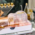 The Painted 2.0 Chanukah Set on a glass shelf - the painted Lucite tray, the menorah with its oil cups and the brachos tabletop, set for Chanukah
