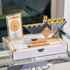 Gold Chanukah Brachos Clock styled on a glass shelf with a menorah tray and an oil jug, set for Hanukkah candle lighting