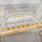 Close-up of the arch Lucite menorah tray, gold להדליק נר של lettering on a pearl marble strip, set for Hanukkah