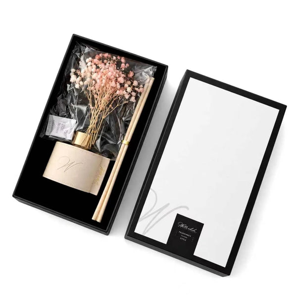 Pink dried flower reed diffuser in a white leather wrap, packed in its open gift box