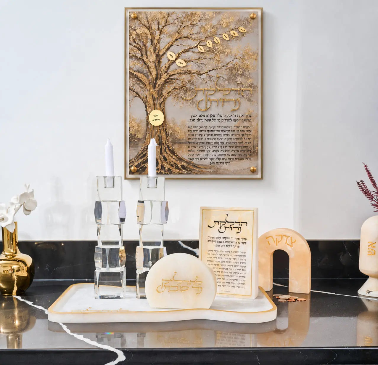 Hadlokas Neiros family tree hung above a Shabbos candle setup with crystal candlesticks, a marble tray and a tzedakah box