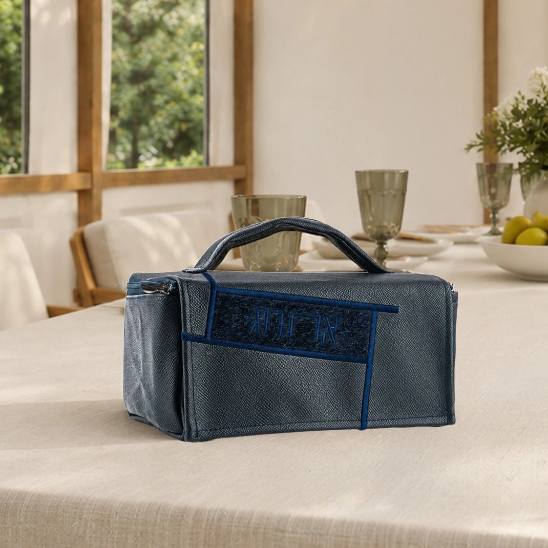 A structured vegan leather esrog bag with a fur front panel, embossed Hebrew lettering. In black and navy for Sukkos.