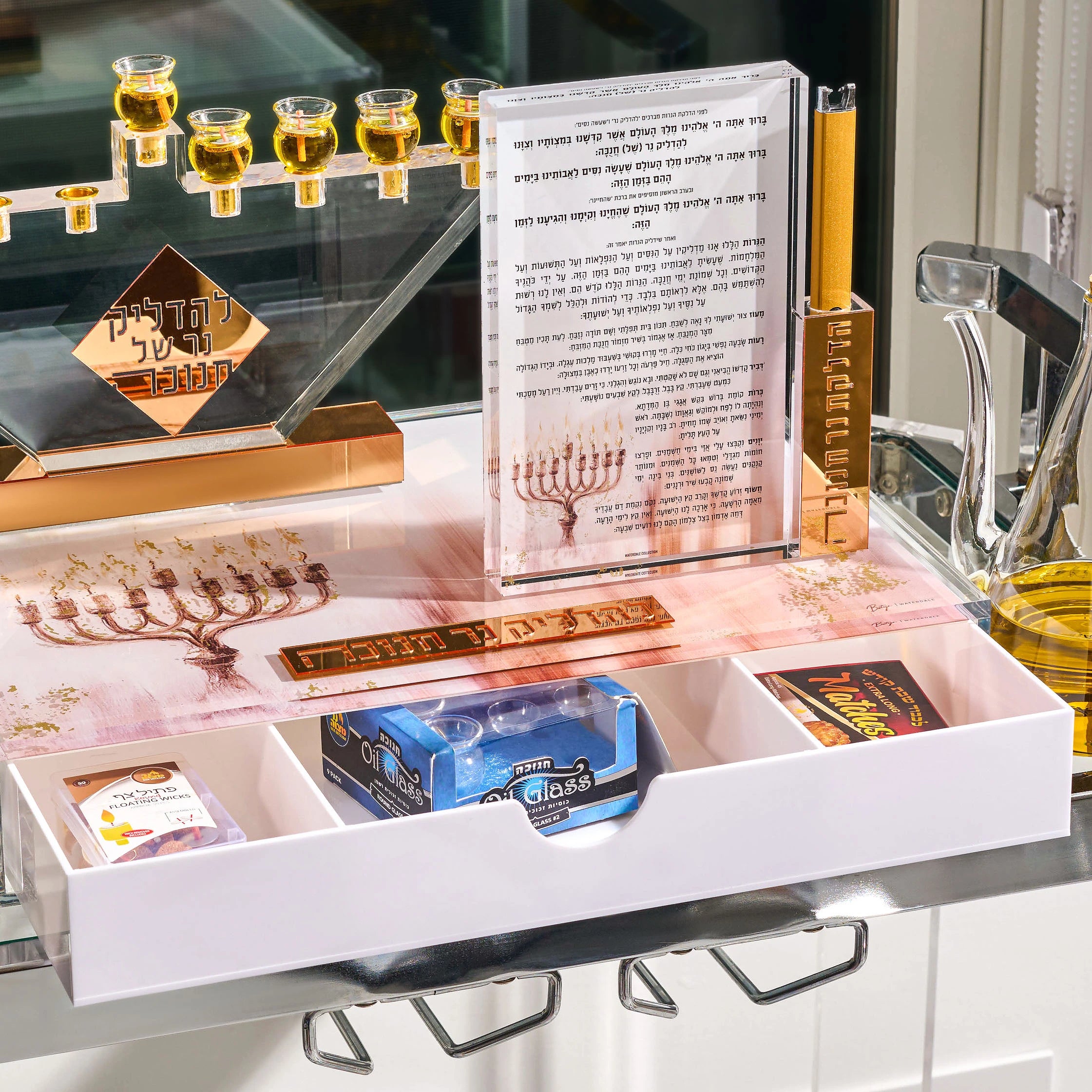 Clear Lucite menorah with gold cups on the painted menorah tray for Chanukah, drawer open showing candles and lighting essentials