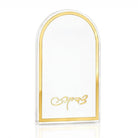A clear Lucite arch-shaped tzedaka box with a polished gold border and gold cursive text at the bottom, displayed on a clean white background with a subtle reflection.