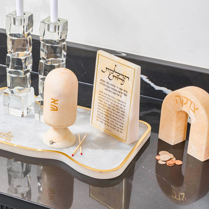 Cream resin arch tzedakah box with Hebrew text, displayed on a resin base with candlesticks and resin match cloche and resin brachos block